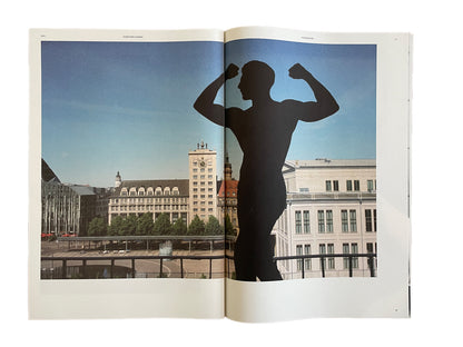 Open book showing a silhouette of a person flexing muscles with a cityscape in the background