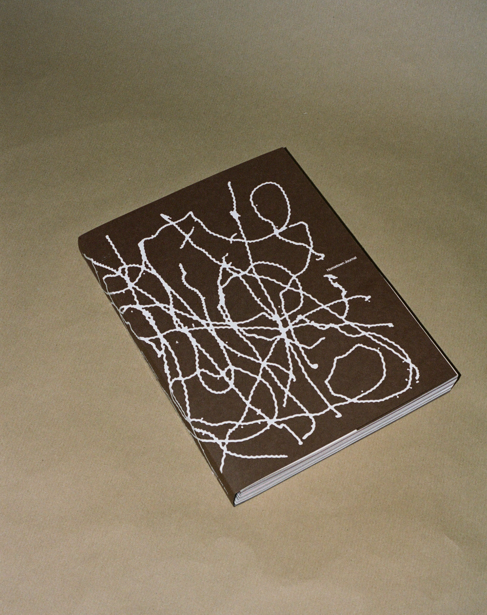 Brown book with white abstract design on a beige background