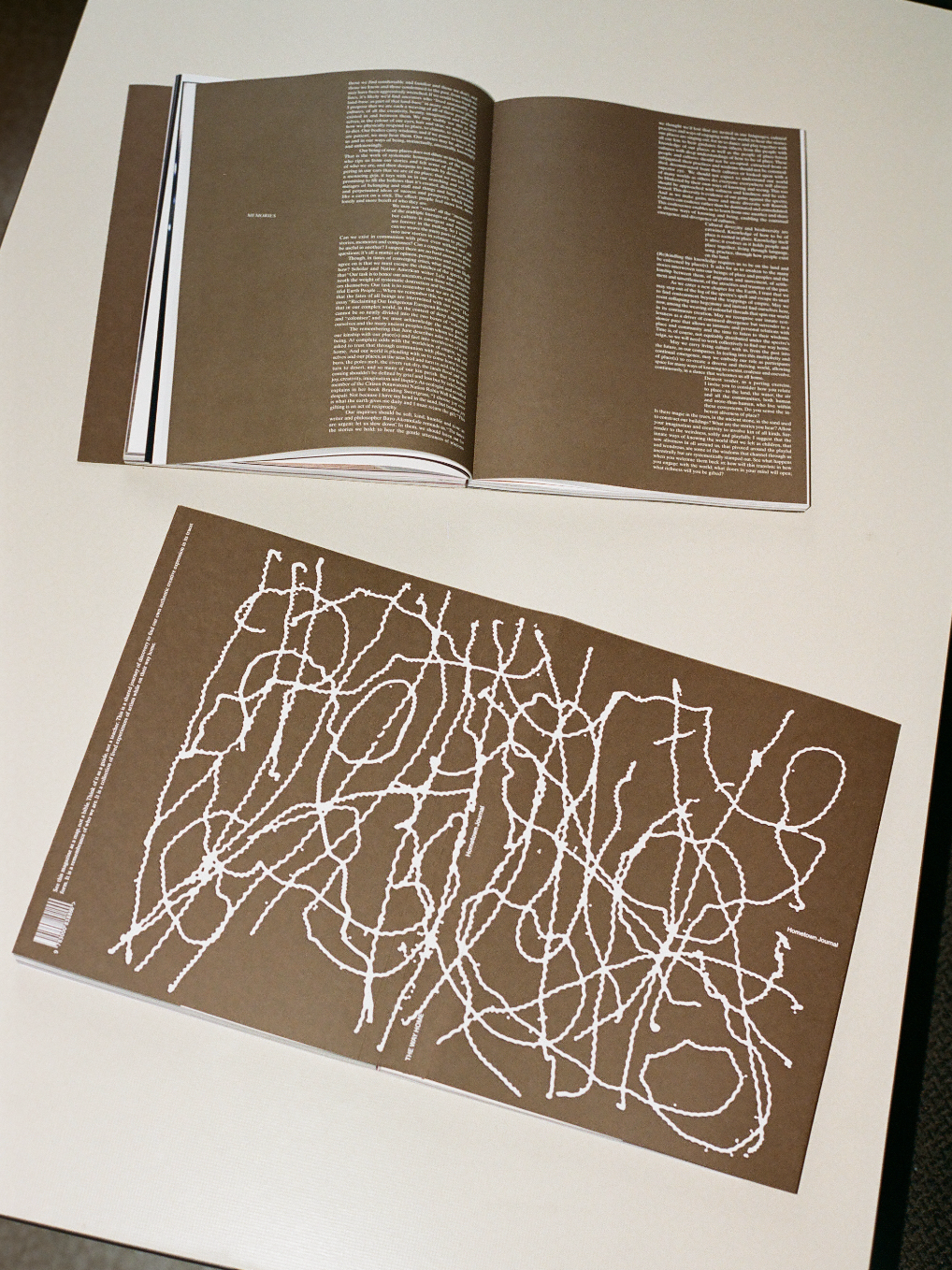 Open book with a brown cover featuring white abstract design on a white surface