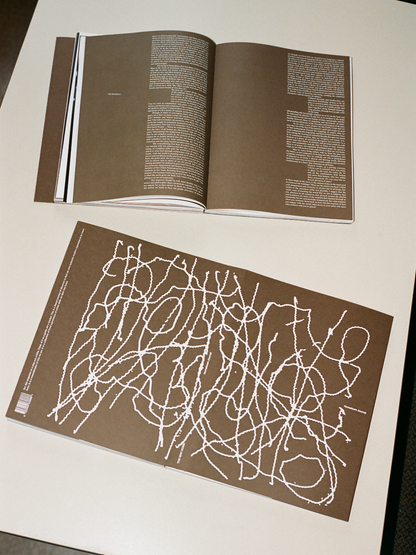 Open book with a brown cover featuring white abstract design on a white surface