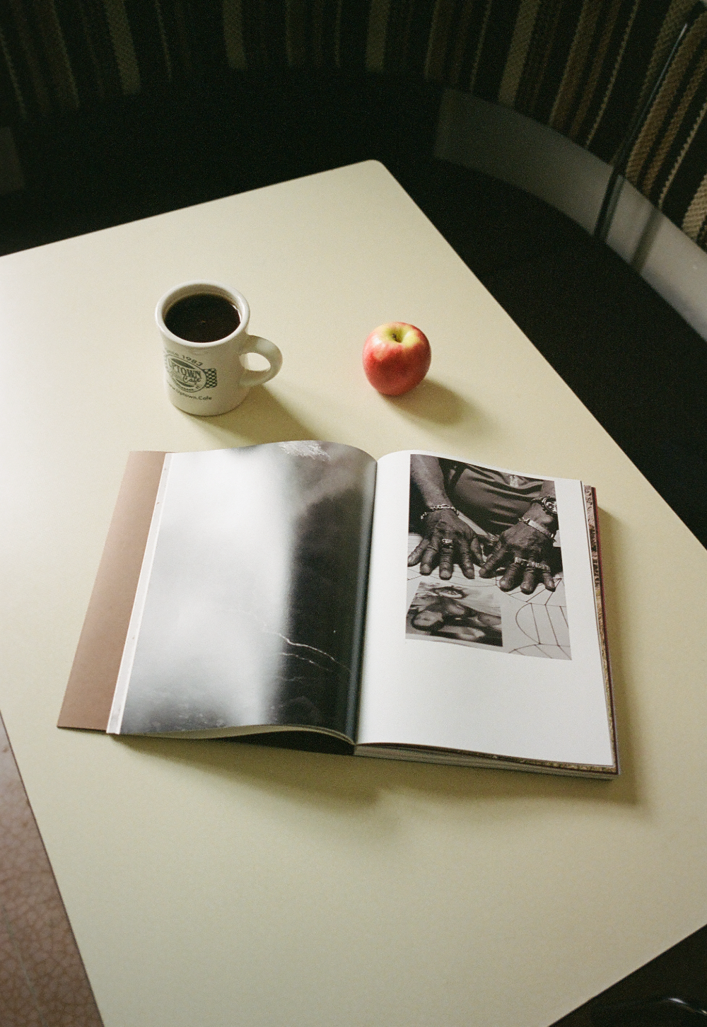 Open book with a coffee cup and apple on a table showing the images of Juan Brenner